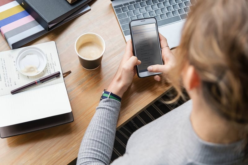 woman+with+laptop+looking+at+mobile-1