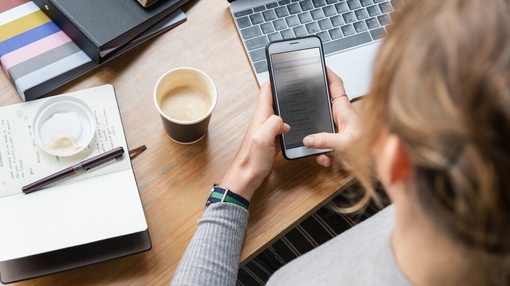 woman+with+laptop+looking+at+mobile